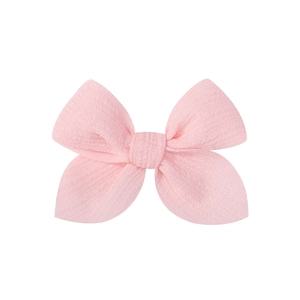 Close-up of pink handmade fabric hair bow clip showing fine texture and stitching