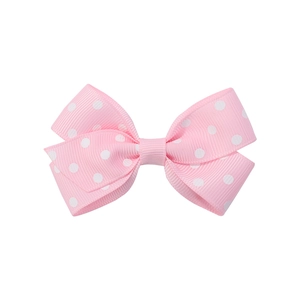 Dettaglio del fiocco rosa a pois in nastro grosgrain con trama a coste per capelli