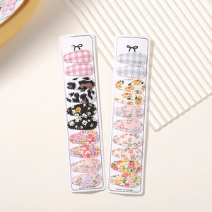 Detailed view of children's floral print BB hair clips set on white paper cards