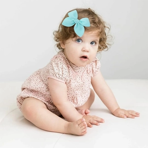 Toddler model wearing a handmade turquoise bow hair clip with textured fabric finish