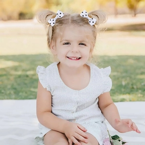 Bambina con due fiocchi per capelli in grosgrain a pois bianchi in un ambiente esterno