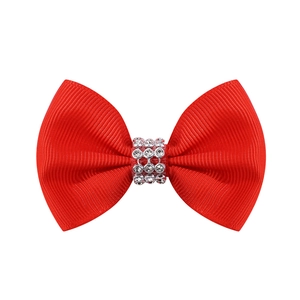 Détail d'une pince à cheveux nœud rouge avec centre orné de strass étincelants