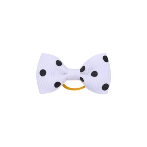 Close-up of a white polka dot grosgrain ribbon bow with a yellow elastic hair band