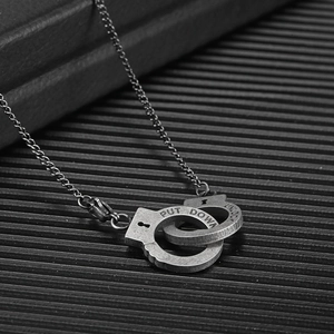 Detail of vintage silver handcuff necklace with PUT DOWN and UNLOCK engraving