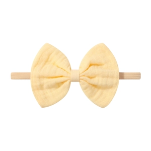Vue détaillée du bandeau bébé avec nœud en coton jaune clair et texture douce