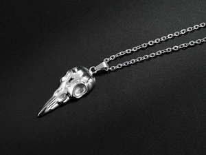 Makro-Detail eines silbernen Rabenschädel-Anhängers aus poliertem Titanstahl mit Kette
