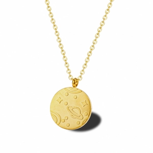 Gros plan du collier médaille dorée avec détails gravés de Saturne et galaxie