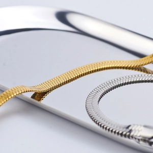 Bracciali a catena piatta a serpente in oro e argento su un vassoio di metallo