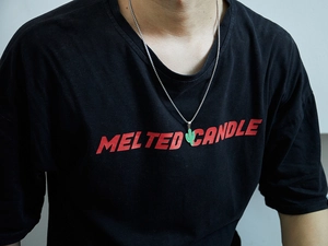 Detailed close-up of a green cactus pendant necklace on a silver chain worn by a model