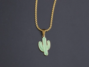 Close-up of golden box chain with green enamel cactus pendant on a dark texture