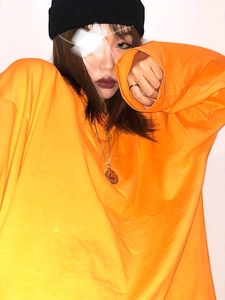 Rotating smile necklace on model wearing an oversized orange sweatshirt and black beanie