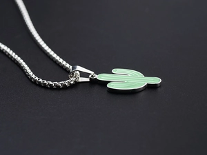 Macro shot of a silver cactus pendant with green enamel on a stainless steel box chain