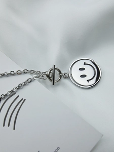 Close-up of rotatable smiley pendant on stainless steel chain with vintage OT toggle clasp
