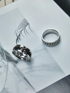 Close-up of rotatable chain rings in silver and black finishes on an artistic background
