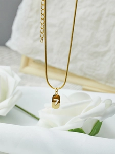 Détail macro du pendentif numéro 7 doré avec une fine chaîne serpent élégante