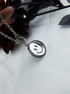Close-up of rotatable smiley face pendant on a silver stainless steel punk necklace