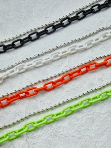 Dettaglio di maglie di catena in acrilico colorato con catenine a sfere argentate assortite