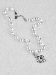 Macro view of pearl and steel chain necklace with heart-shaped crystal pendant detail
