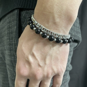 Detail of double-layer Cuban link and black bead bracelet for men on wrist