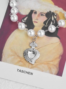 Macro view of pearl necklace featuring a silver heart pendant with a clear gemstone center