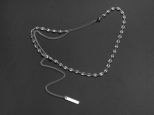 Macro detail of silver coffee bean link necklace with minimalist rectangular pendant tag