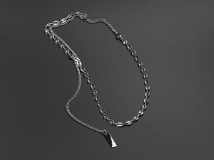 Detail of silver pig nose chain with polished rectangular pendant on grey textured surface