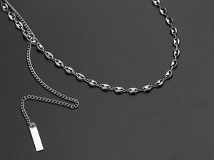 Detail of silver pig nose chain necklace with rectangular pendant on a matte background