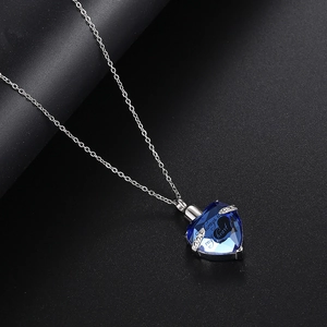 Vista detallada del colgante de cristal azul en forma de corazón con grabado conmemorativo