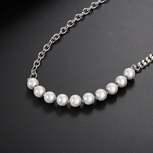 Macro detail of titanium steel chain with ten grey pearls on a black background