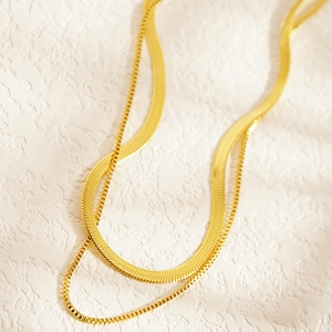 Gros plan détaillé d'une chaîne serpent et boîte dorée double couche sur fond texturé