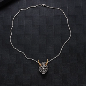 Detailed view of gothic Hannya mask pendant with golden horns and silver steel chain
