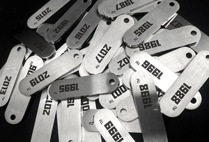 Détail macro des pendentifs en acier titane brossé avec numéros d'année gravés