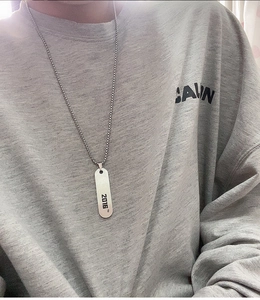 Gros plan du collier avec pendentif rectangulaire argenté et gravure 2016 sur pull