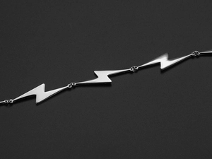 Macro detail of polished stainless steel lightning bolt pendant with smooth shiny surface