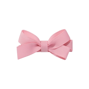 Détail du ruban gros-grain rose et de la texture de la barrette à double nœud
