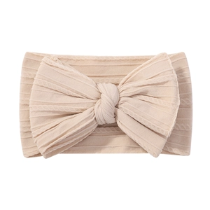 Detailed view of apricot baby headband featuring a large bow and ribbed knit texture