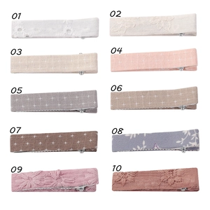 Vue détaillée du lot de 10 barrettes en lin et dentelle aux motifs variés pour enfants