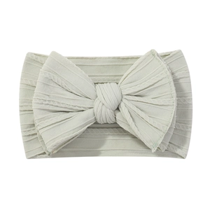 Detailed texture of mint green ribbed nylon baby headband with a soft elastic bow
