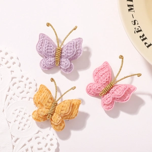 Macro detail of three handmade crochet butterfly clips in purple, pink and yellow yarn