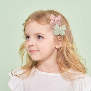 Lot de barrettes papillon en cuir PU pour enfants en rose et vert sur un jeune modèle