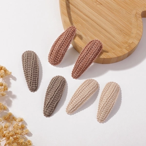 Detailed close-up of handmade knitted BB hair clips in three warm candy colors