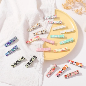 Flat lay of colorful floral fabric hair clips set on a textured white background