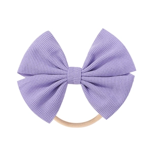 Detailed view of purple fabric bow on soft seamless nylon headband for infants