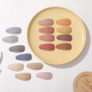 Detail of tear-drop cloth hair clips in muted solid colors on a round tray