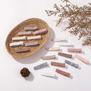 Detail view of 15 handmade floral fabric hair clips in a woven basket with a rustic vibe