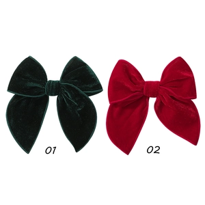 Detailed close-up of vintage red and dark green velvet bow hair clips with soft texture