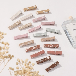 Detailed view of assorted Morandi colored fabric hair clips with floral embroidery prints
