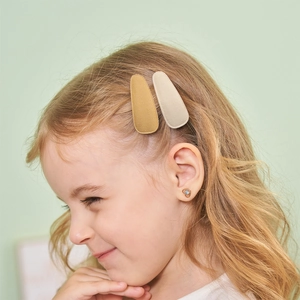 Child model wearing cream and gold fabric BB hair clips with woven texture finish