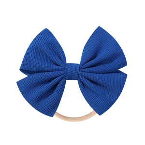 Detailed close-up of dark blue knitted bow on a soft seamless nylon baby headband