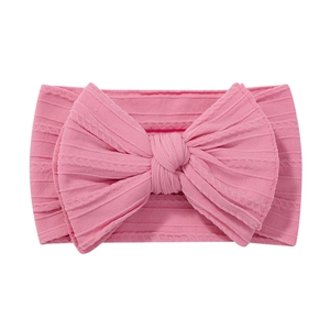 Pink stretchy nylon baby headband with a large textured knit bow on a white background